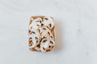 Overhead shot of fresh sliced champignon mushrooms in a box on a light surface.